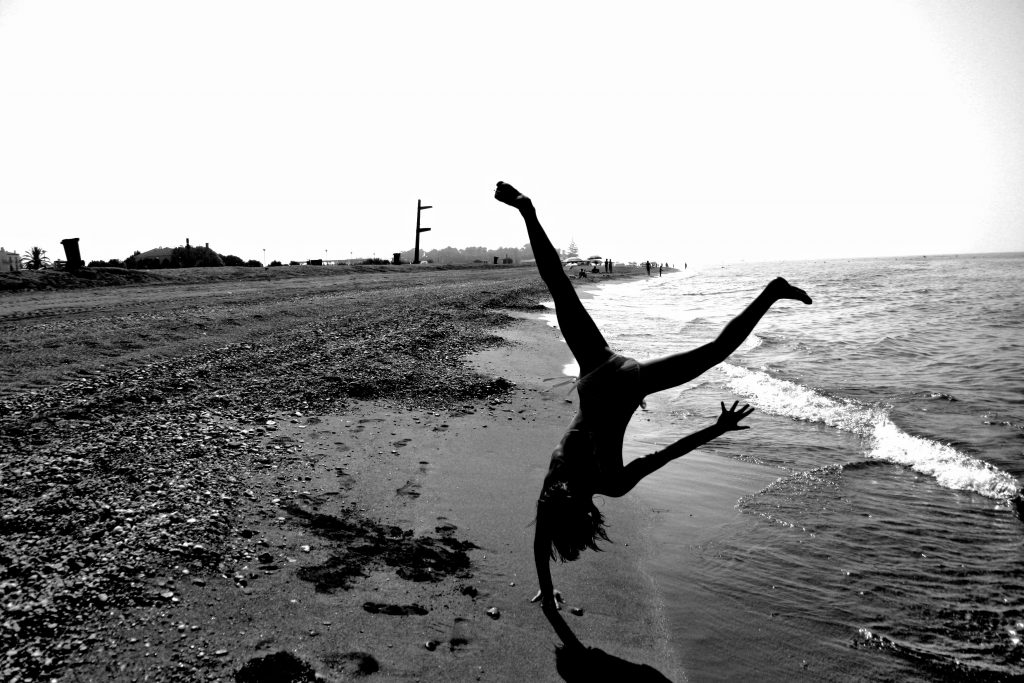 Woman doing cartwheel on beach